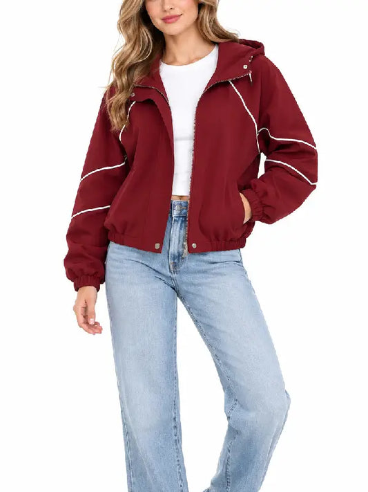 Woman wearing a burgundy hooded zip-up jacket with white piping, front view, styled with a white top and light blue jeans