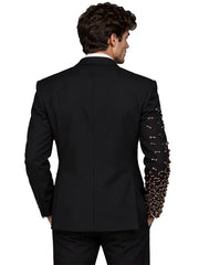 Full-length back view of men's black tailored suit featuring a clean structured jacket and embellished sleeve detail against a neutral gray studio background.