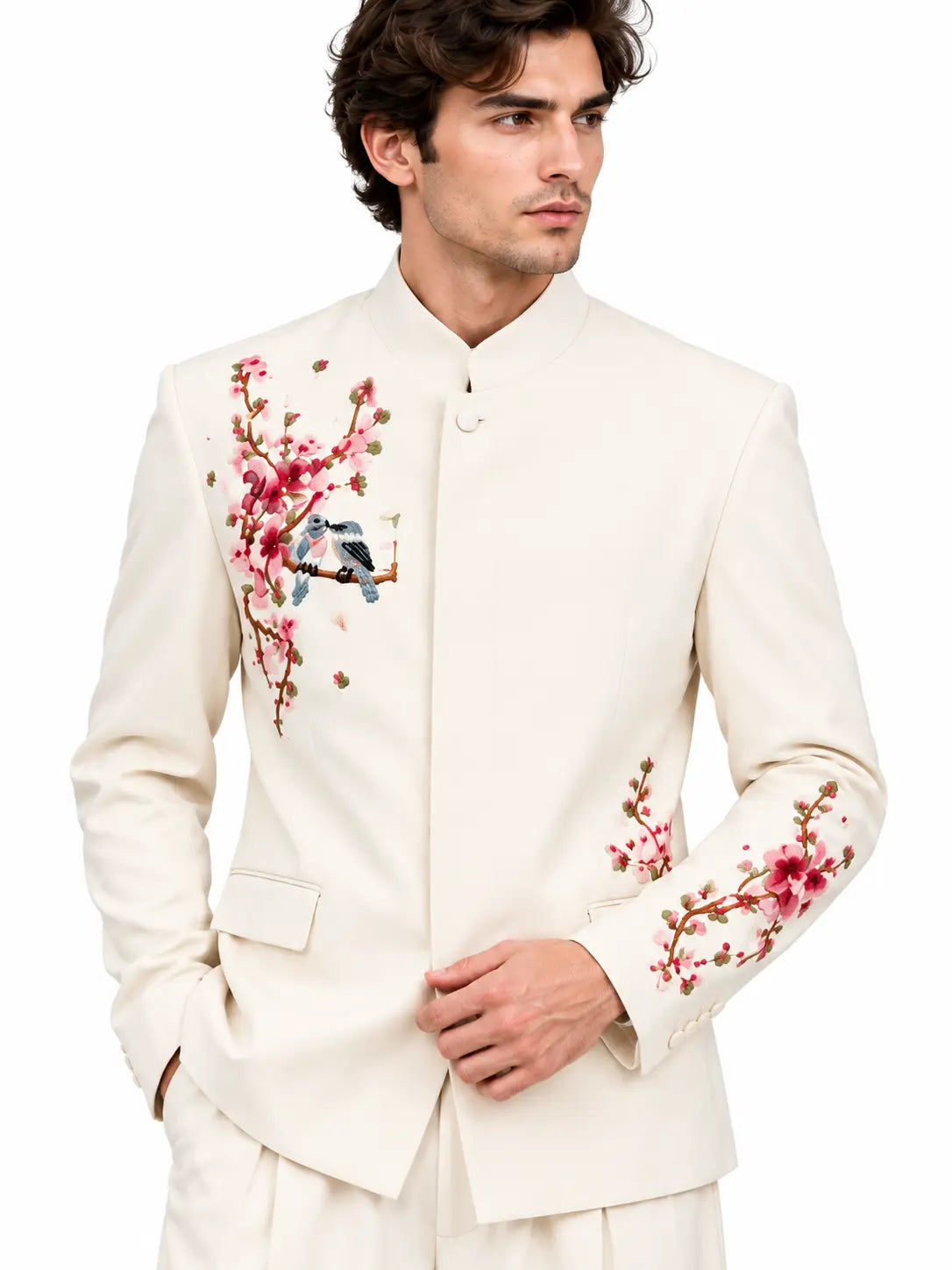 Close-up front view of men's ivory suit showing detailed pink blossom and bird embroidery on the jacket.
