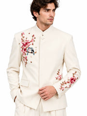 Close-up front view of men's ivory suit showing detailed pink blossom and bird embroidery on the jacket.