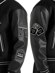 Close-up of black wool varsity jacket with leather sleeves, contrast piping and embroidered patches