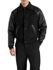 Men's black wool and leather raglan letterman jacket with snap-button closure and angled pockets.