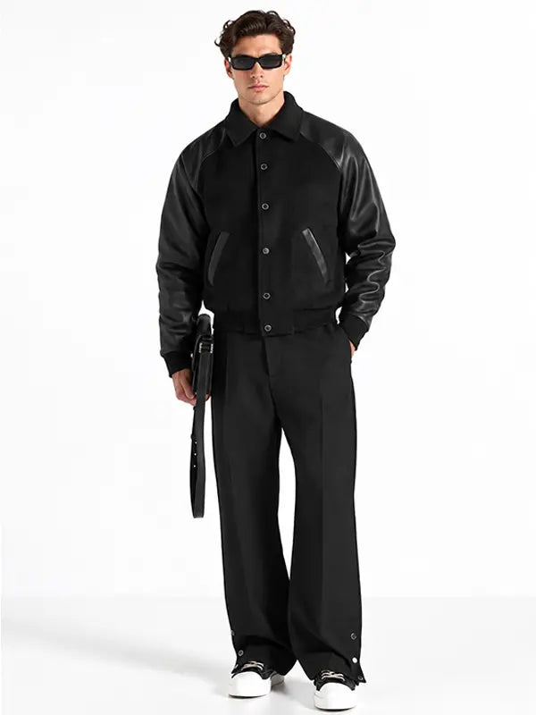 Men's black wool and leather raglan letterman jacket with snap-button closure and angled pockets.