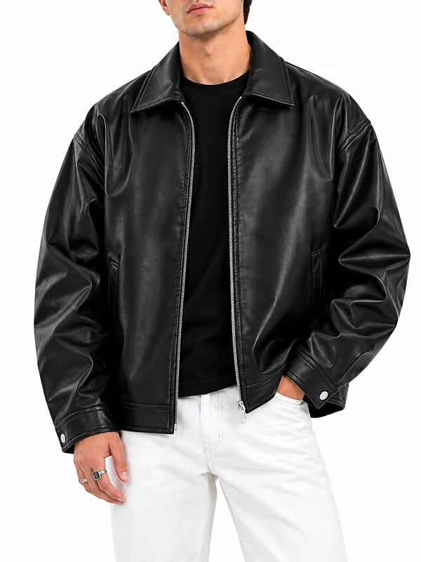 Man wearing an oversized black leather bomber jacket with zip front and shirt collar, styled with a black tee and white jeans