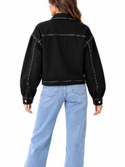 Back view of women’s black cropped utility jacket with white contrast stitching worn with light-wash jeans