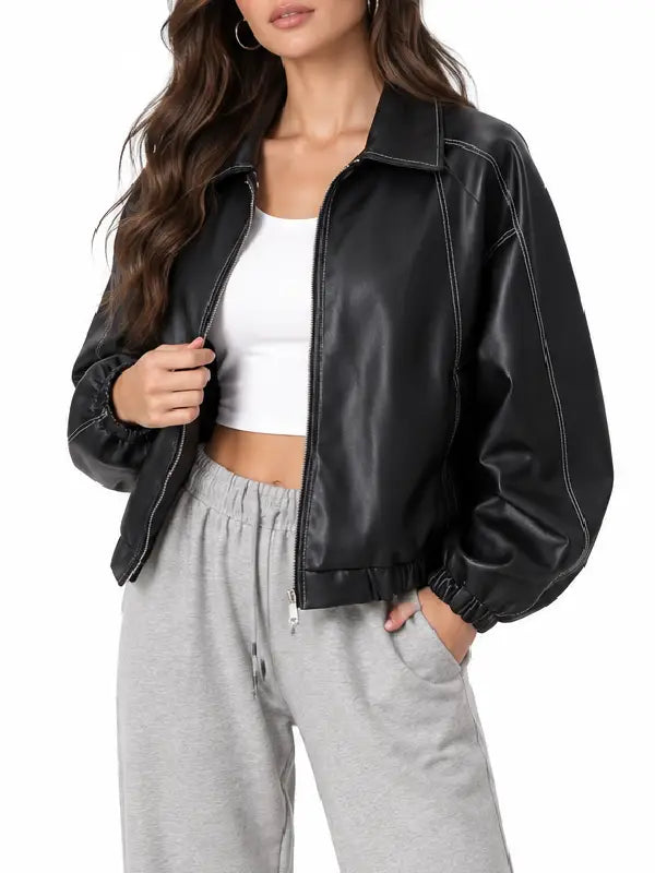 Woman wearing a black leather bomber jacket with shirt collar and ribbed cuffs, close-up front view