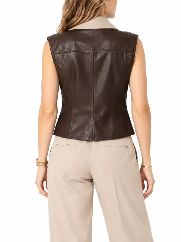 Back view of woman wearing a brown sheepskin leather vest with beige collar and back seams with cream trousers