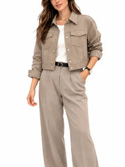 Woman wearing a taupe two-piece set with a cropped snap button jacket, chest pockets, and pleated wide leg pants