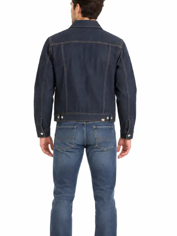 Back view of man wearing dark rinse wash denim trucker jacket with jeans and white sneakers