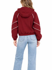 Back view of a women's burgundy hooded jacket with white piping on the sleeves and an elastic hem