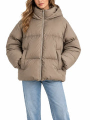 Woman wearing a taupe oversized hooded puffer jacket, front view, unzipped hood up
