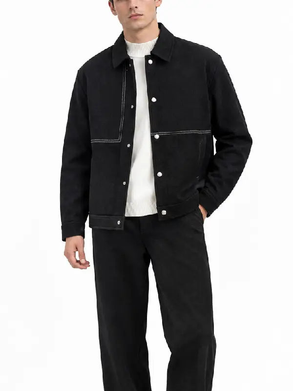 Man wearing a black denim snap button jacket with white contrast stitching over a white knit sweater, front view