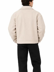 Back view of men's beige oversized biker jacket with snap button cuff tabs, worn with black trousers