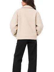 Back view of women's beige oversized biker jacket with dropped shoulders, worn with black pants