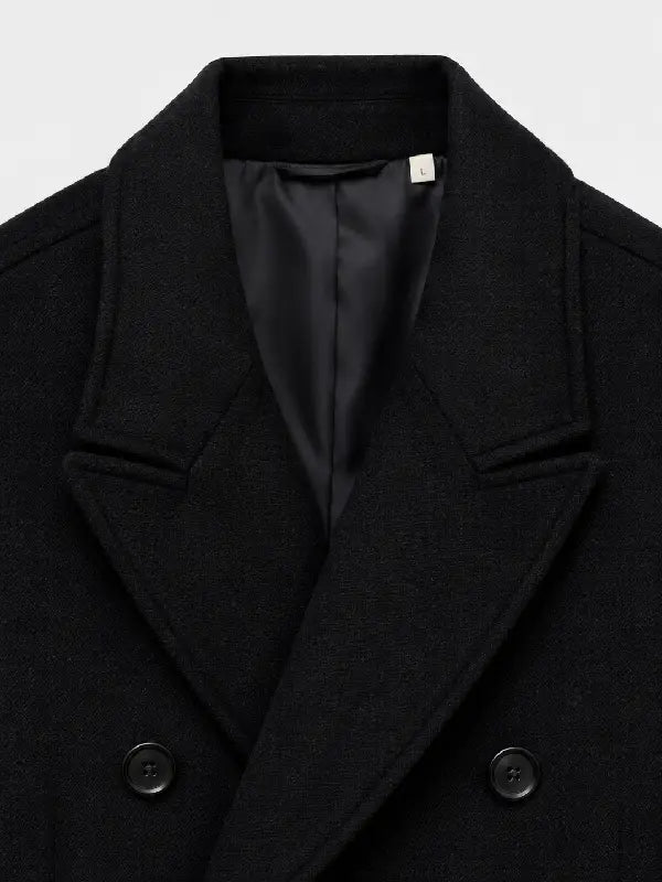 Close-up of black wool overcoat lapel, collar, and button detail