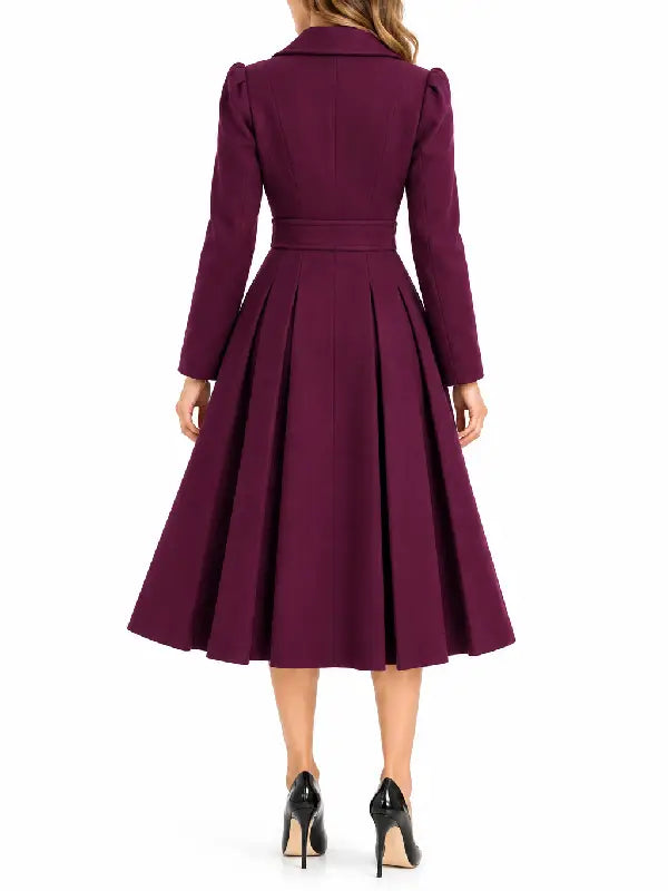 Back view of a woman wearing a burgundy pleated midi coat with a waist panel and puff shoulders