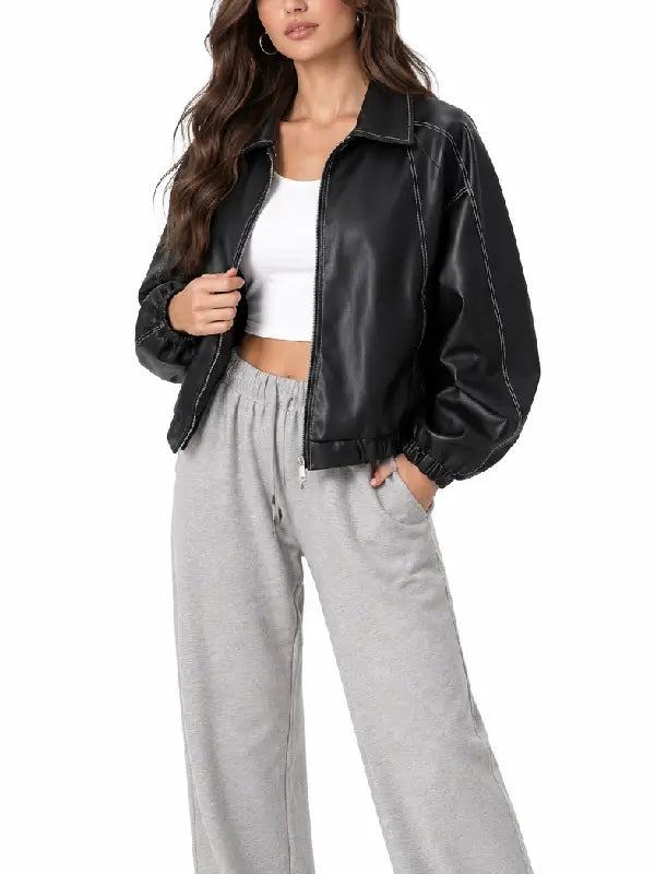 Front view of a women’s oversized black leather bomber jacket styled with a white top and grey joggers