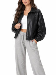 Front view of a women’s oversized black leather bomber jacket styled with a white top and grey joggers