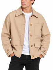 Front view of man wearing a beige chore jacket with button front, chest pocket and flap pockets over a white tee