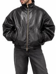 Man wearing an oversized black leather bomber jacket with stand collar and gold zip front, close-up front view