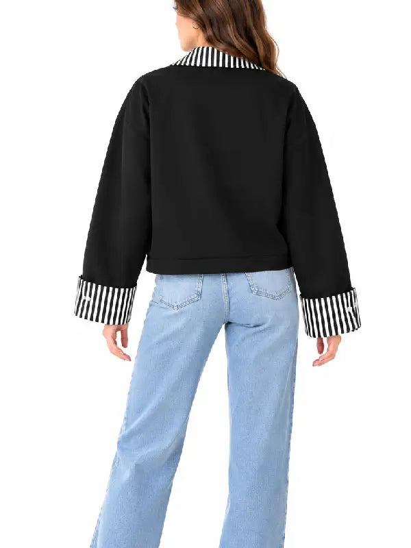 Back view of women’s black cropped jacket with striped collar and wide folded striped cuffs worn with light-wash jeans