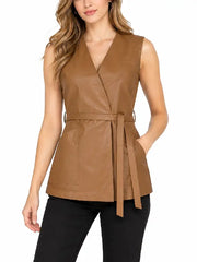 Front view of woman wearing a tan leather wrap vest with V-neck, tie belt and patch pockets over black pants