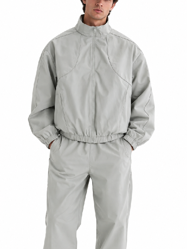 Man wearing light grey oversized track jacket and pants set, front view, zipped up