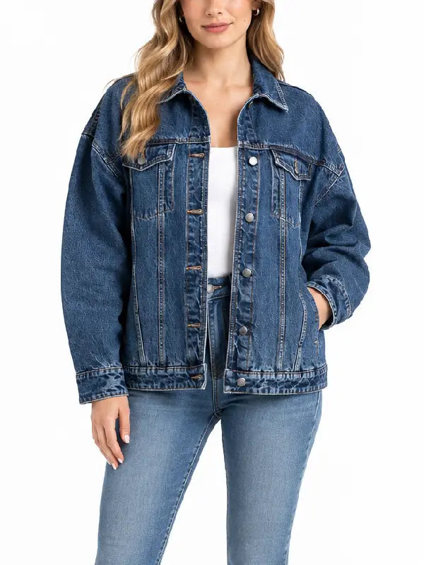 Woman wearing oversized medium wash denim trucker jacket, front view, unbuttoned