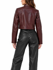 Back view of women’s burgundy cropped leather jacket with stand collar and slim long sleeves worn with black leather pants