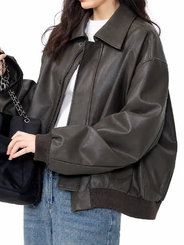 Woman wearing a brown vintage bomber jacket with turn-down collar, concealed zip, and ribbed cuffs