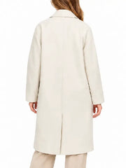 Back view of woman wearing ivory button-front topcoat with tan pants