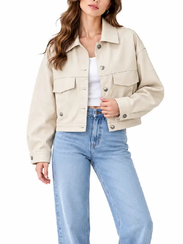 Front view of women’s cream cropped button jacket with shirt collar, chest flap pockets, and snap closure worn with light-wash jeans