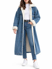 Front view of woman wearing long blue denim sherpa coat open over white top, jeans, and black belt