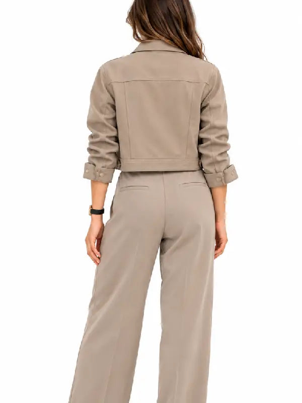 Back view of a woman wearing a taupe cropped jacket with button cuffs and matching wide leg pants