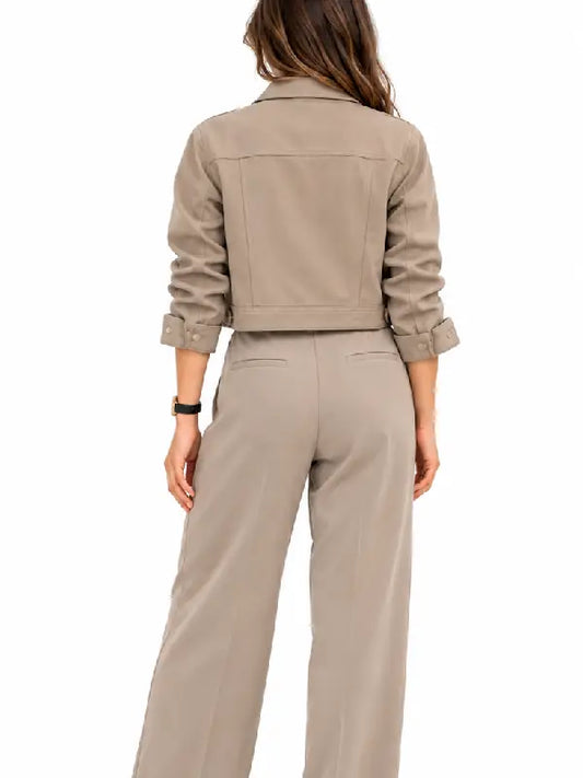 Back view of a woman wearing a taupe cropped jacket with button cuffs and matching wide leg pants
