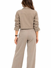 Back view of a woman wearing a taupe cropped jacket with button cuffs and matching wide leg pants